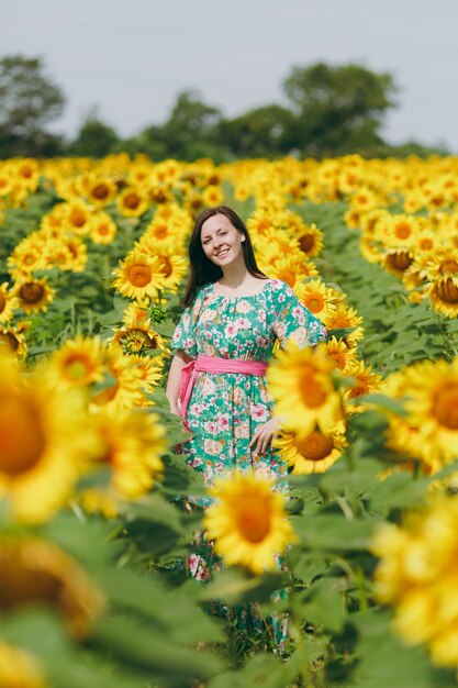 La ragazza bruna in un campo di girasoli