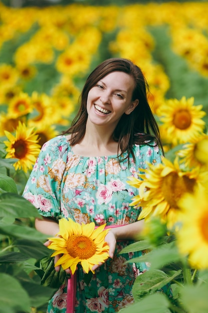 La ragazza bruna in un campo di girasoli