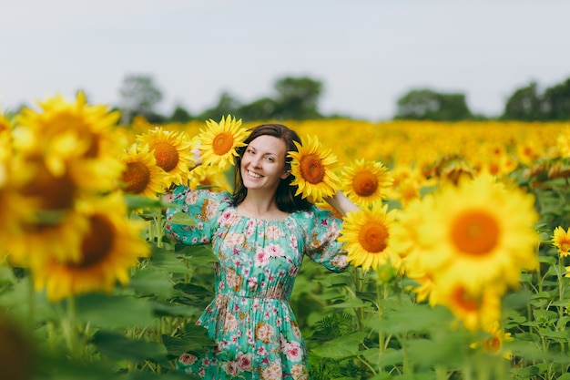 La ragazza bruna in un campo di girasoli