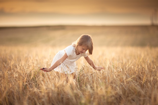 La ragazza cammina nel campo con la segale allo stile di vita al tramonto