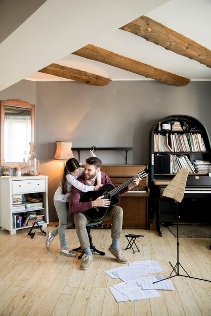 La ragazza carina e il suo bel padre stanno suonando la chitarra