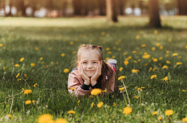 La ragazza carina in età scolare si trova sull'erba nel parco in estate