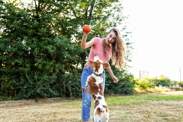 La ragazza carina sta giocando con il suo cane nel parco