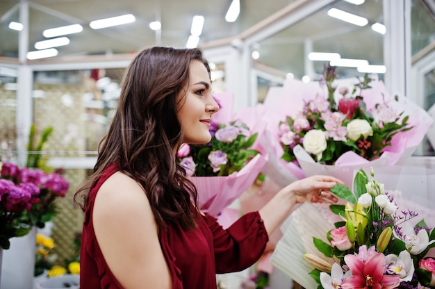 La ragazza castana nell'affare rosso fiorisce al deposito di fiore.