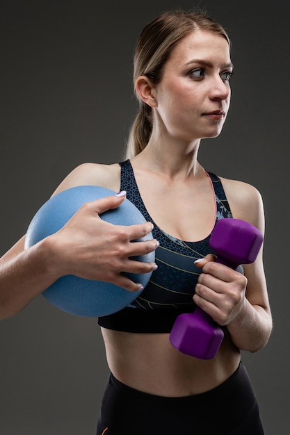 La ragazza caucasica di sport con la figura esile fa gli esercizi con la palla blu isolata su fondo nero