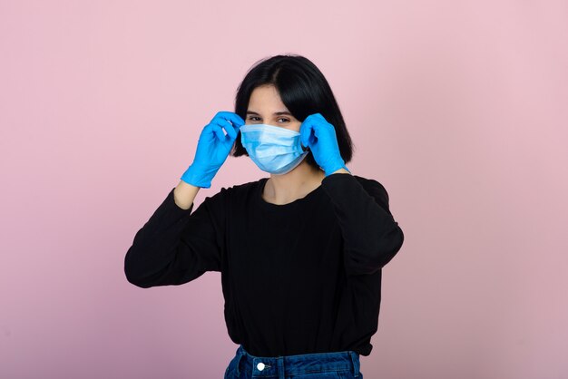 La ragazza caucasica in maschera protettiva di colore blu. Ritratto sparato sopra fondo rosa. concetto di protezione da virus e inquinamento.