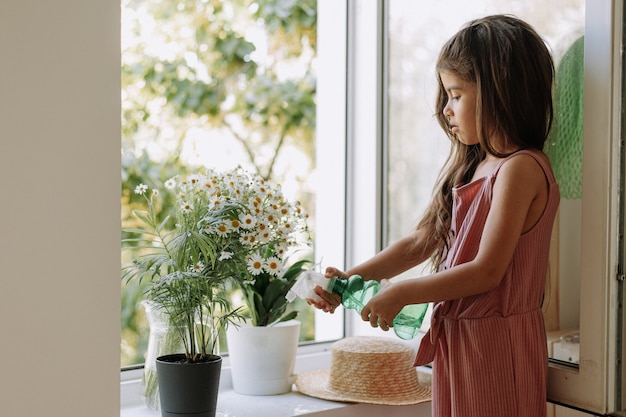 la ragazza caucasica irriga il fiore una finestra aperta concetto di giardinaggio domestico