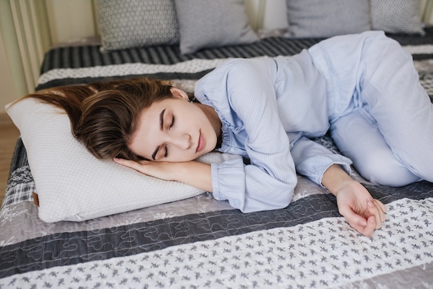 La ragazza che dorme in pigiama sul letto nella sua stanza. Elegante interno grigio-bianco.