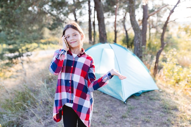 La ragazza che parla al cellulare. Ragazza adolescente in piedi vicino a una tenda e tenendo il telefono cellulare