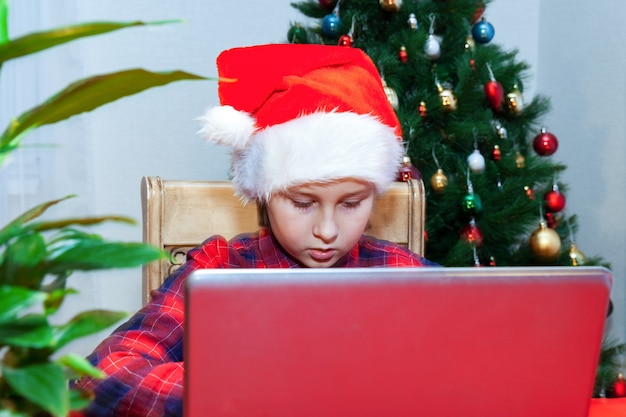 La ragazza chiacchiera sul laptop sullo sfondo dell'albero di Natale