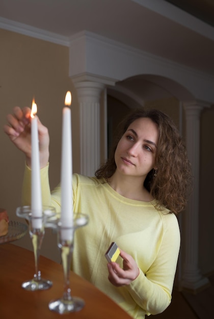 La ragazza con capelli lunghi accende le candele nella cucina a casa