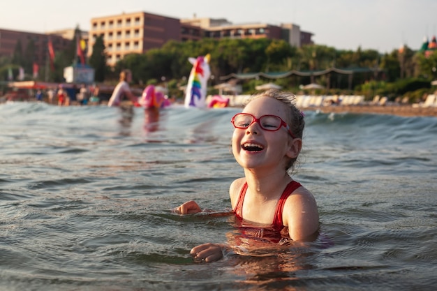 La ragazza con gli occhiali si bagna nel mare blu