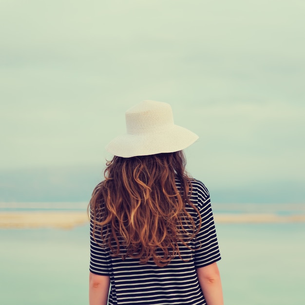 La ragazza con i capelli biondi brillanti va in riva al mare