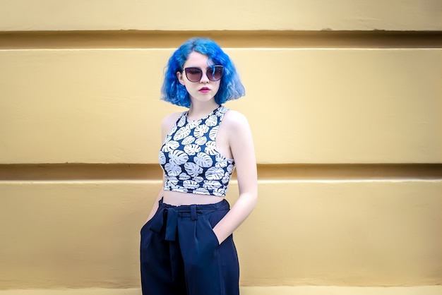 La ragazza con i capelli blu sul muro giallo