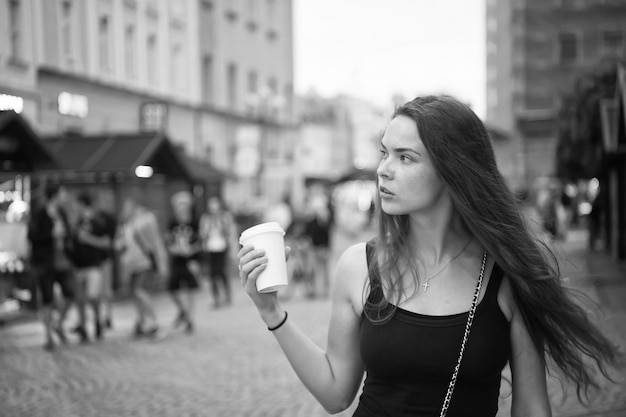 La ragazza con i capelli lunghi cammina sulla strada della città di sera viaggiando