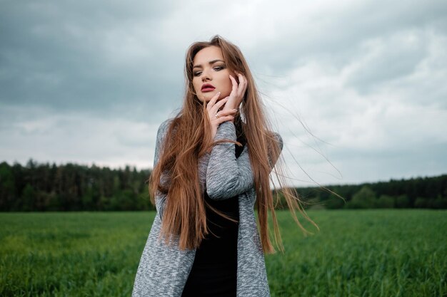 La ragazza con i capelli lunghi sta nel campo nel vento Il concetto di libertà e passione