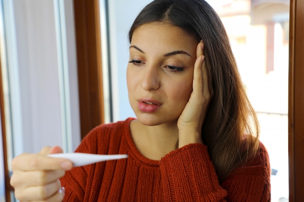 La ragazza con i sintomi della malattia da Coronavirus 2019 controlla la febbre.