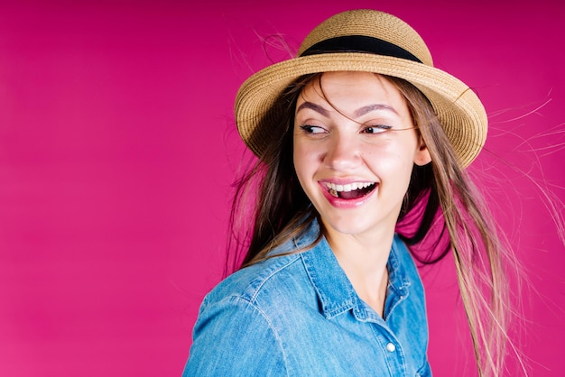 La ragazza con il sorriso più ampio si guarda alle spalle. sfondo rosa