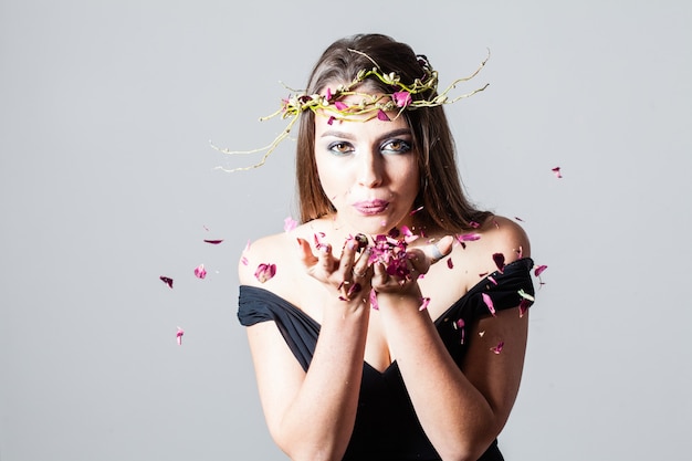 La ragazza con il trucco alla moda ha sparso i petali di rose secchi