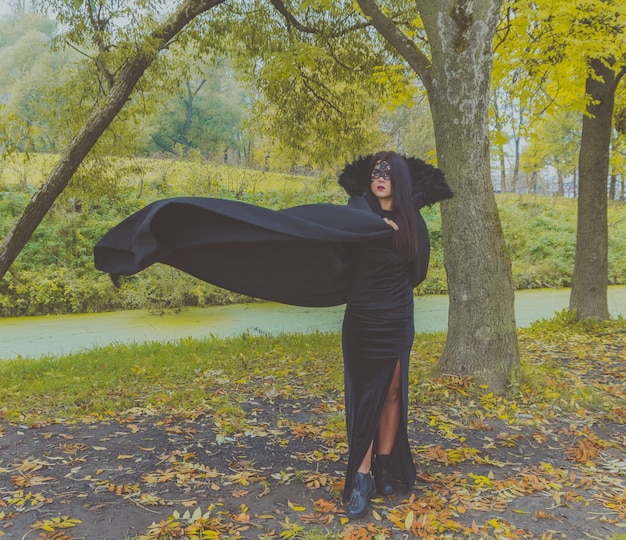 La ragazza con il vestito nero e la maschera alza il suo abito.