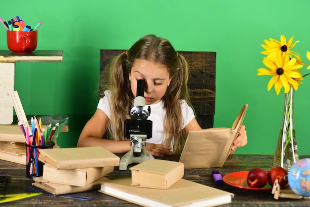La ragazza con la faccia attenta esamina il microscopio Scienza e istruzione