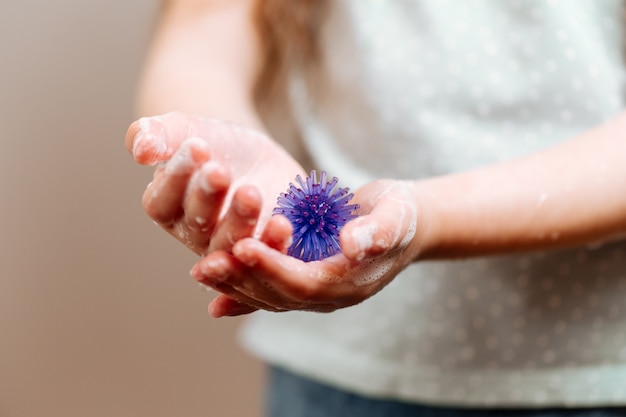 La ragazza con le mani in sapone detiene un modello astratto di coronavirus.