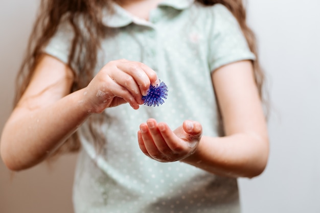 La ragazza con le mani in sapone detiene un modello astratto di coronavirus.