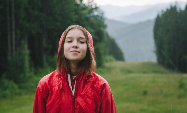 La ragazza con un impermeabile rosso si trova in montagna sullo sfondo di un bellissimo paesaggio