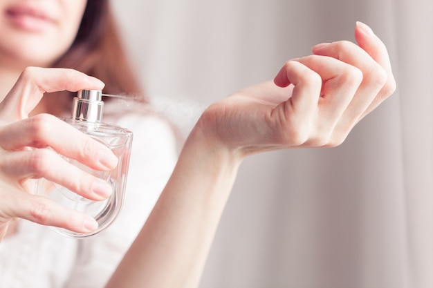 La ragazza con un vestito bianco si spruzza il profumo sul polso