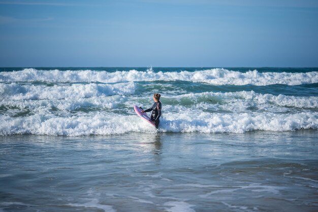 La ragazza con una tavola da surf vince le onde. Concept: Superamento, Determinazione, incredibile bellezza