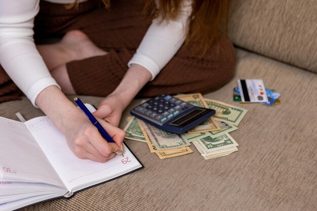 La ragazza conta il budget conta su una calcolatrice e lo annota su un taccuino