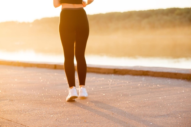 La ragazza corre al tramonto. Foto ritagliate di piedi con scarpe da ginnastica bianche