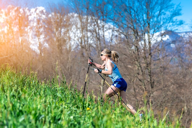 La ragazza corre con i bastoni in montagna