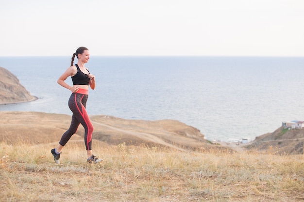 La ragazza corre in montagna sull'oceano.