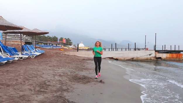 La ragazza corre lungo la spiaggia al mattino presto