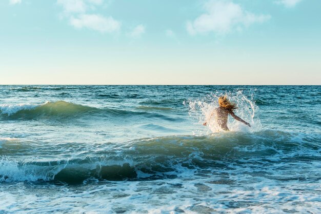 La ragazza corre verso il mare in tempesta con uno spray