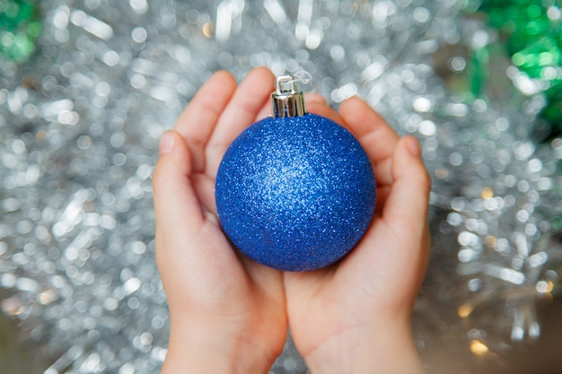 La ragazza dà una palla dell'albero di Natale. Decorazione dell'albero di Natale nel palmo della ragazza