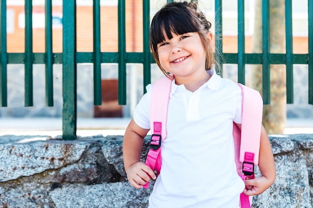 La ragazza dai capelli neri che indossa uno zaino rosa va a scuola