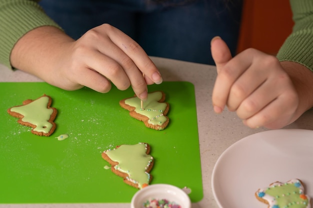 La ragazza decora i pan di zenzero con glassa di zucchero Buon Natale e felice anno nuovo concetto