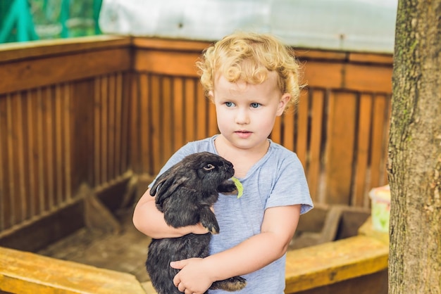 La ragazza del bambino accarezza e gioca con il coniglio nello zoo delle carezze. concetto di sostenibilità, amore per la natura, rispetto per il mondo e amore per gli animali. Ecologico, biologico, vegano, vegetariano