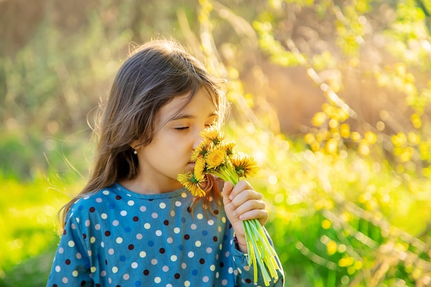 La ragazza del bambino annusa i fiori del dente di leone