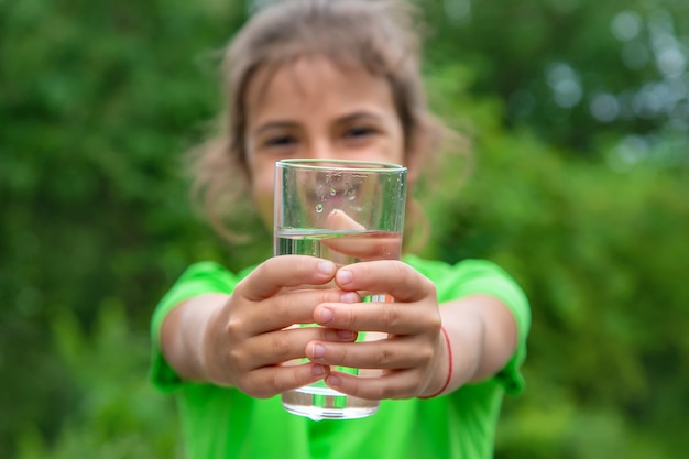 La ragazza del bambino beve l'acqua da un bicchiere. Messa a fuoco selettiva. Ragazzo.