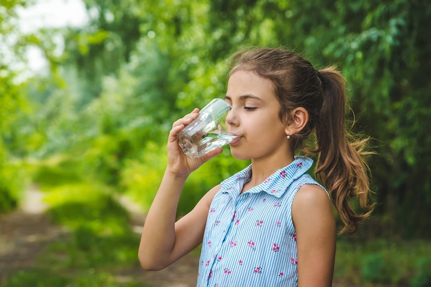 La ragazza del bambino beve l'acqua da un bicchiere.