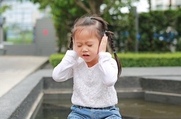 La ragazza del bambino che tiene le sue mani copre le orecchie per non sentire.