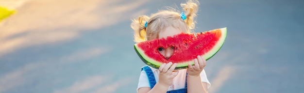 La ragazza del bambino mangia l'anguria in estate Messa a fuoco selettiva