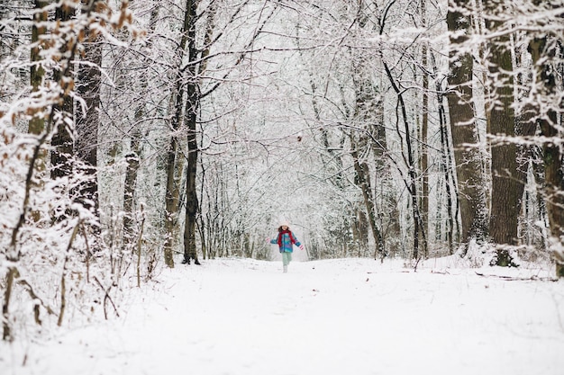 La ragazza del bambino si diverte a correre tra gli alberi di neve nel periodo invernale, concetto di felicità.