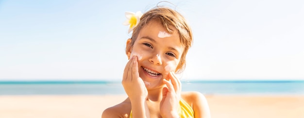 La ragazza del bambino spalma la crema solare sul viso