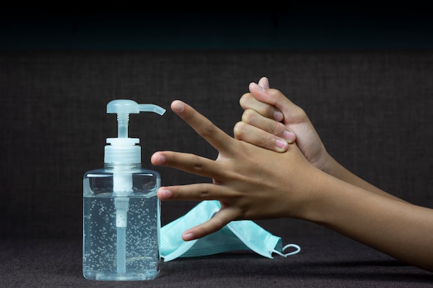 La ragazza del bambino usa il disinfettante per le mani per pulire la mano.