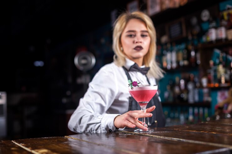 La ragazza del barista crea un cocktail al pub