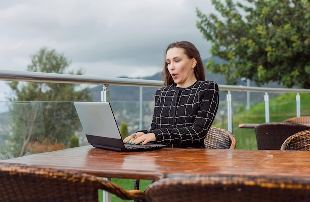 La ragazza del blogger sta lavorando al computer portatile sullo sfondo della vista della natura